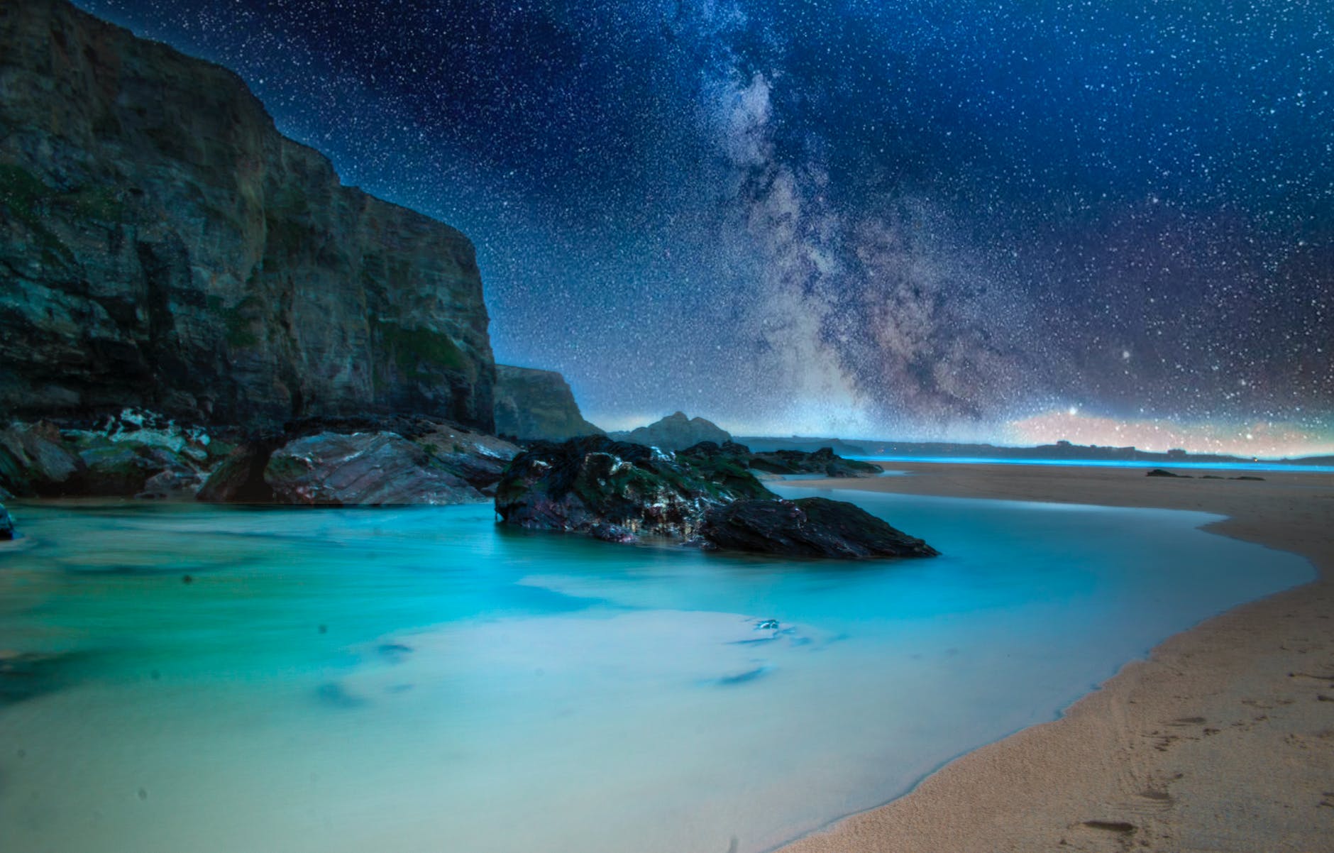 ocean with rock formation under starry night